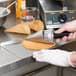 A person using a Carnival King waffle cone forming tool to make a waffle cone on a counter.