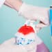 A person using a dispenser to make a snow cone with red liquid.