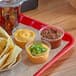 A clear plastic tray with a variety of dips including a clear plastic container of brown liquid.