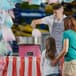 A man in an apron making cotton candy with a Carnival King cotton candy machine on a counter.