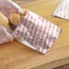 A person in gloves putting a hamburger in a Carnival King paper bag.