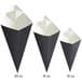 Three black and white Carnival King cardboard fry cones.