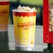 A yellow Carnival King popcorn bucket filled with popcorn on a table.