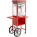 A red Carnival King popcorn machine on a cart with wheels.