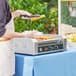 A person using a Carnival King hot dog roller grill to cook hot dogs.