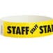 A yellow paper wristband with black "STAFF" text.