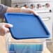 A person holding a Carnival King blue lid on a clear plastic container.