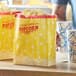 Two yellow Carnival King popcorn bags on a table.