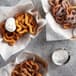 A sieve with white powder on top of a group of Carnival King Funnel Cakes in baskets.