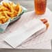 A hot dog in a Carnival King paper wrapper next to a basket of fries.