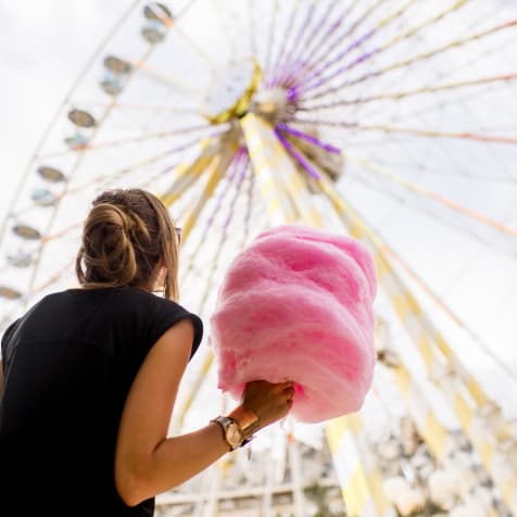 girl holding cotton candy at a carnival