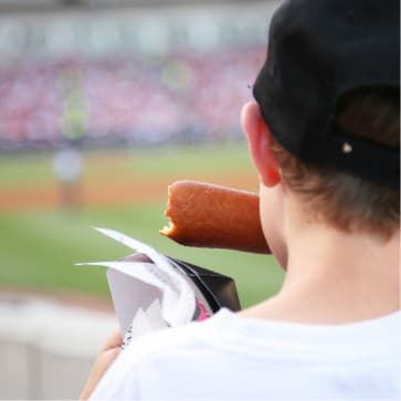 boy eating corndog at baseball game